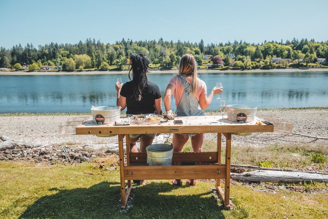 Two friends shucking oysters and toasting champagne at Hood Canal
