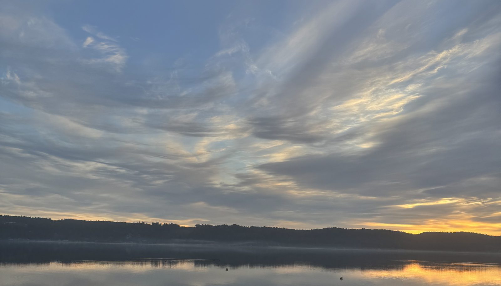 Hood Canal at dawn — glassy water reflecting dramatic clouds over the Olympic Peninsula